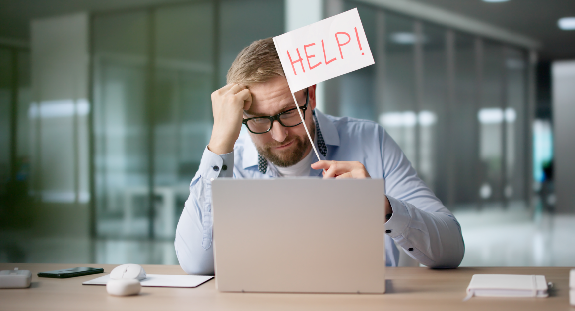 man at desk holding help sign